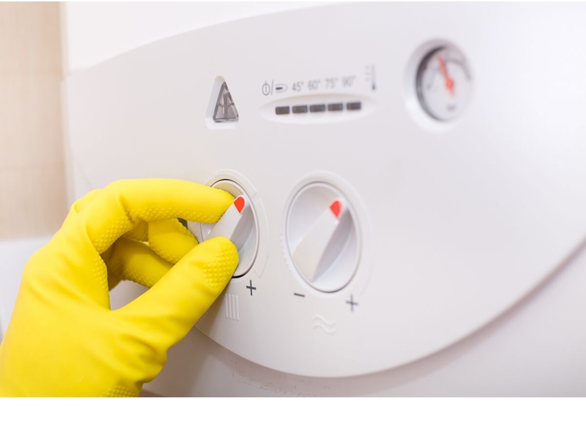 image showing a hand in yellow glove switching a boiler off